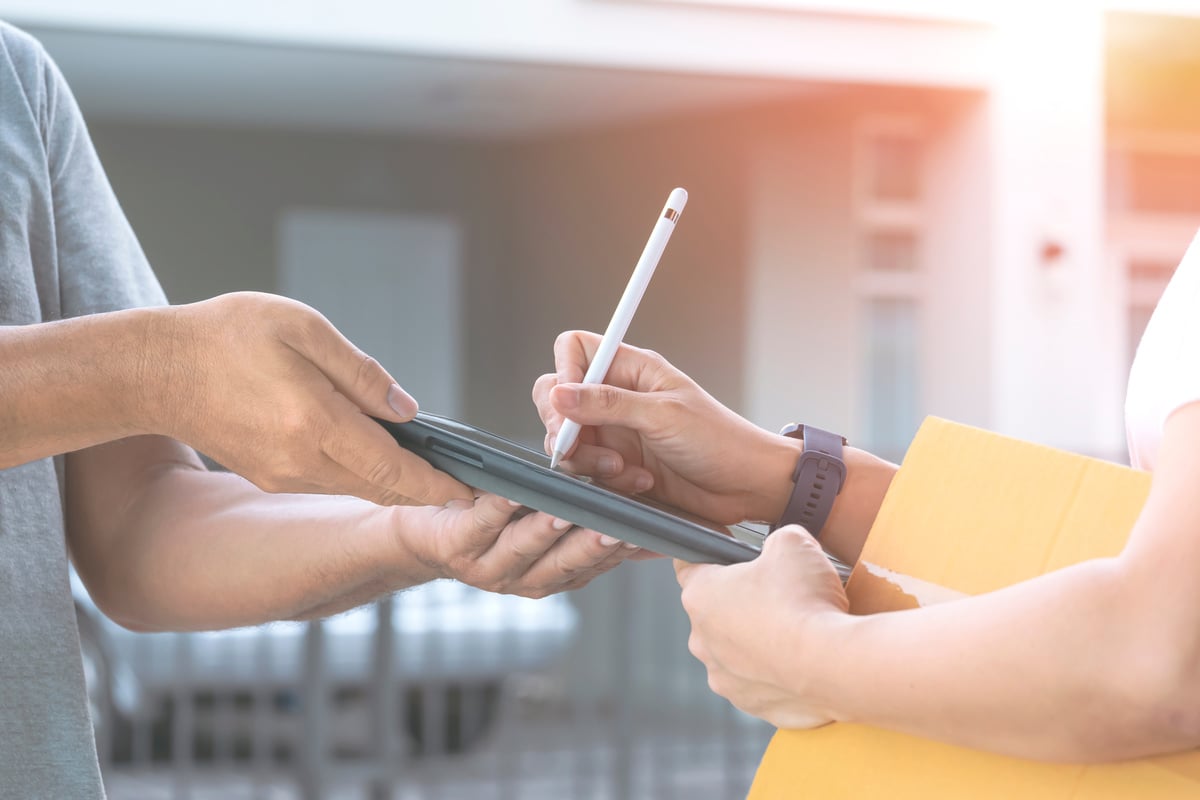 Woman Receiving a Package by Signing Electronically 